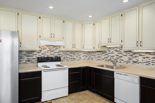 kitchen featuring white appliances, a sink, under cabinet range hood, and cream cabinets