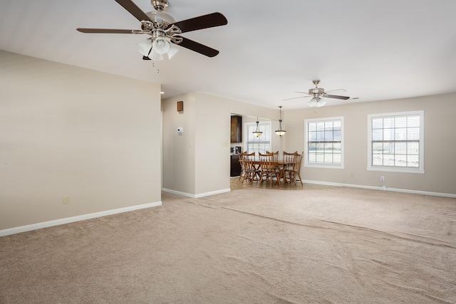 unfurnished living room with a ceiling fan, carpet flooring, and baseboards