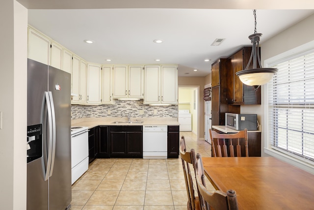 kitchen featuring washer / dryer, appliances with stainless steel finishes, light countertops, a sink, and light tile patterned flooring