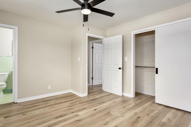 unfurnished bedroom featuring a closet, connected bathroom, light hardwood / wood-style floors, and ceiling fan