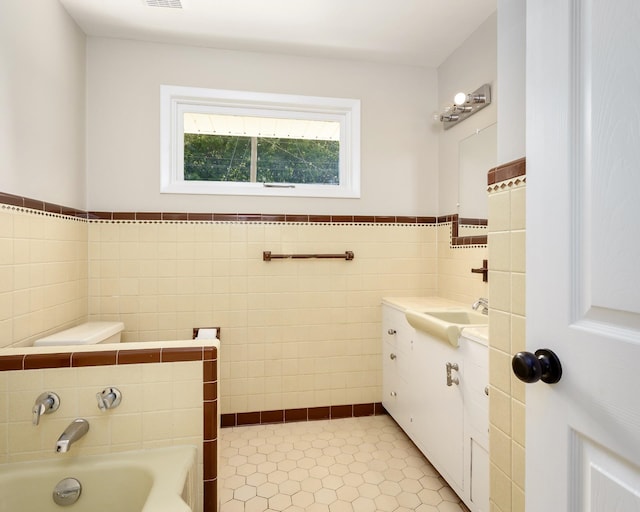 bathroom with a washtub, vanity, tile walls, and tile patterned flooring