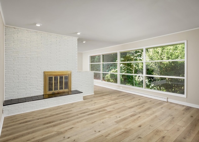 unfurnished living room with light hardwood / wood-style floors, ornamental molding, and a brick fireplace