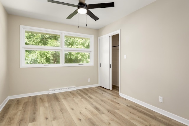 unfurnished bedroom featuring ceiling fan, a closet, light hardwood / wood-style flooring, and a baseboard radiator