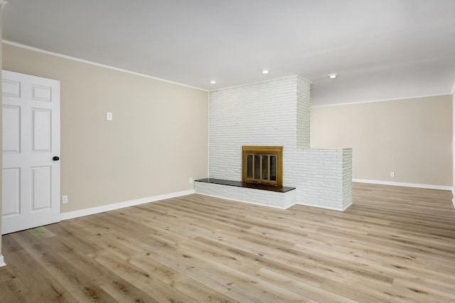 unfurnished living room featuring crown molding, light wood-type flooring, and a brick fireplace