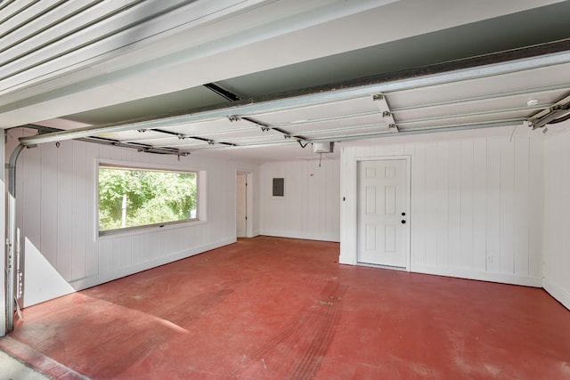 garage featuring electric panel, wood walls, and a garage door opener