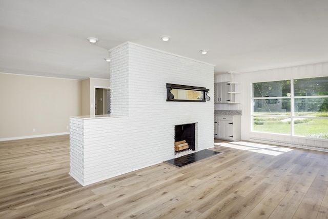 unfurnished living room with light hardwood / wood-style floors and a brick fireplace