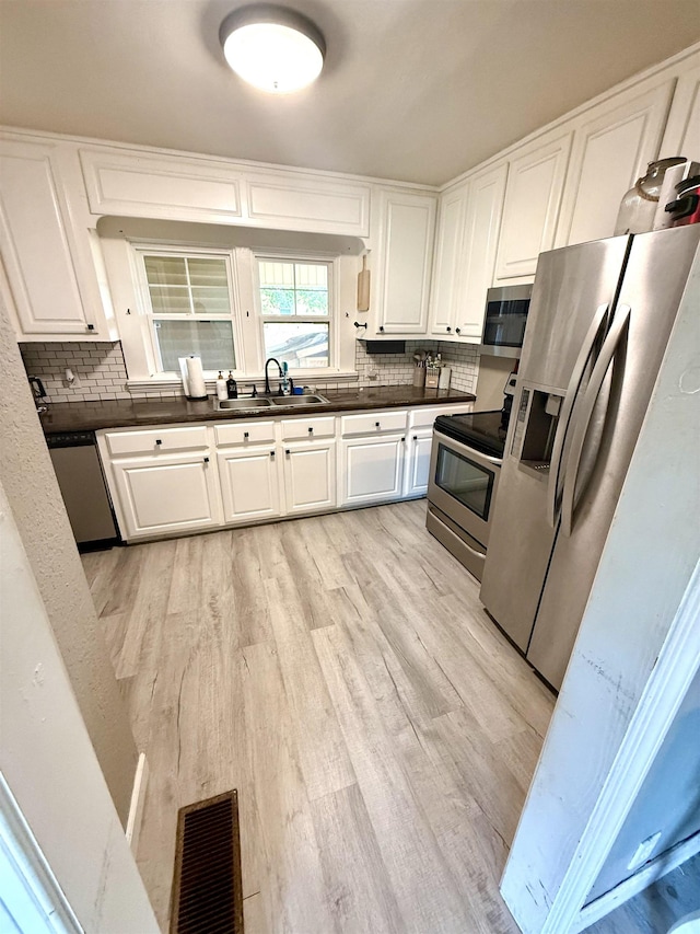  - kitchen featuring a sink, stainless steel appliances, backsplash, and light wood-type flooring