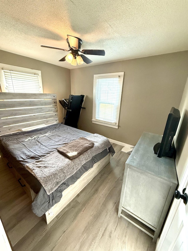  - bedroom with multiple windows, wood finished floors, a textured ceiling, a ceiling fan, and baseboards