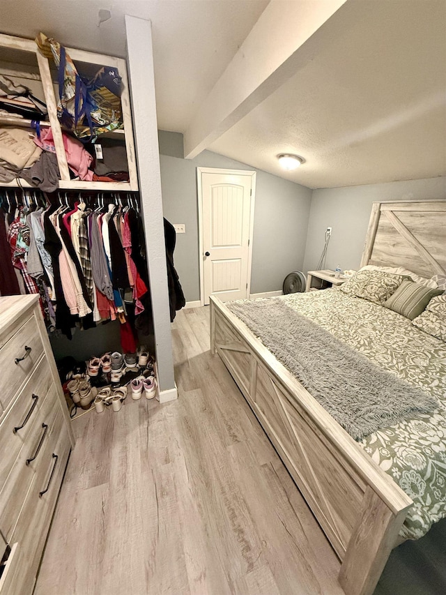  - bedroom featuring light wood finished floors, beam ceiling, a closet, and baseboards