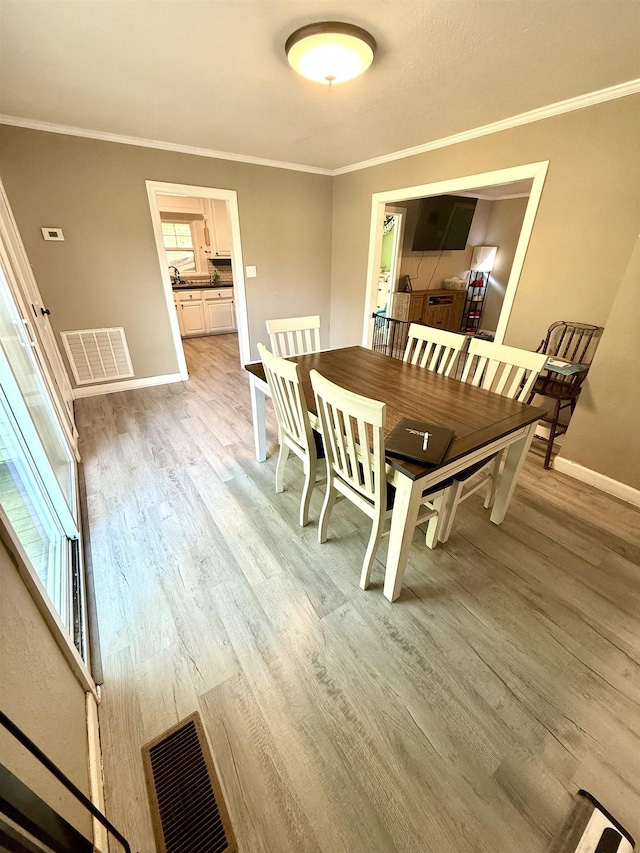  - dining room with light wood-style flooring, baseboards, and crown molding