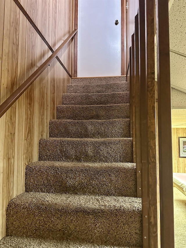 stairway featuring wood walls