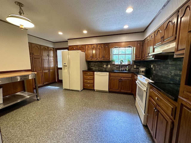 kitchen featuring crown molding, dark countertops, white appliances, under cabinet range hood, and a sink