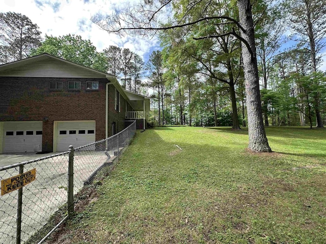 view of yard featuring an attached garage, fence, and driveway