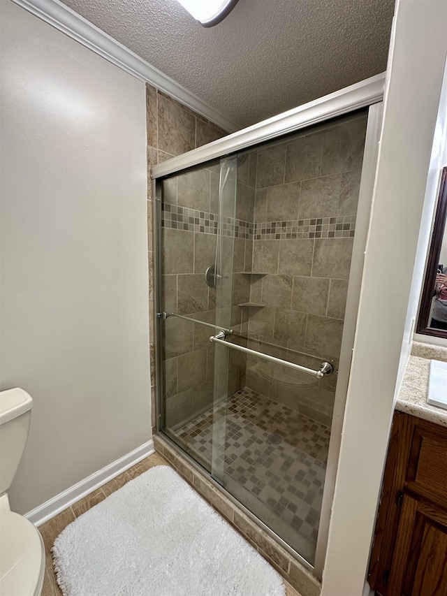 bathroom with toilet, a textured ceiling, baseboards, a shower stall, and ornamental molding