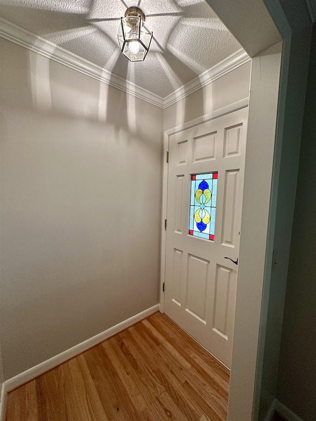 entryway with crown molding, baseboards, light wood finished floors, and a textured ceiling