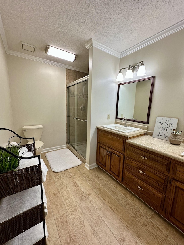 bathroom with crown molding, vanity, toilet, wood finished floors, and a stall shower