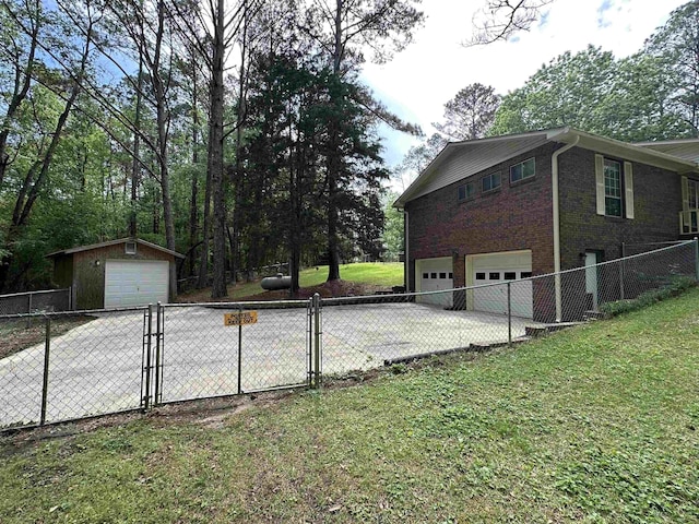 view of side of home featuring brick siding, a garage, a gate, a yard, and driveway