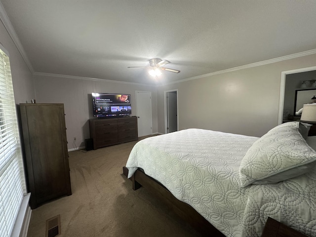 carpeted bedroom with crown molding, a ceiling fan, and visible vents