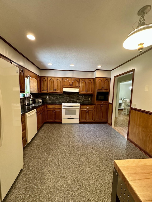 kitchen featuring dark countertops, a sink, white appliances, decorative backsplash, and under cabinet range hood