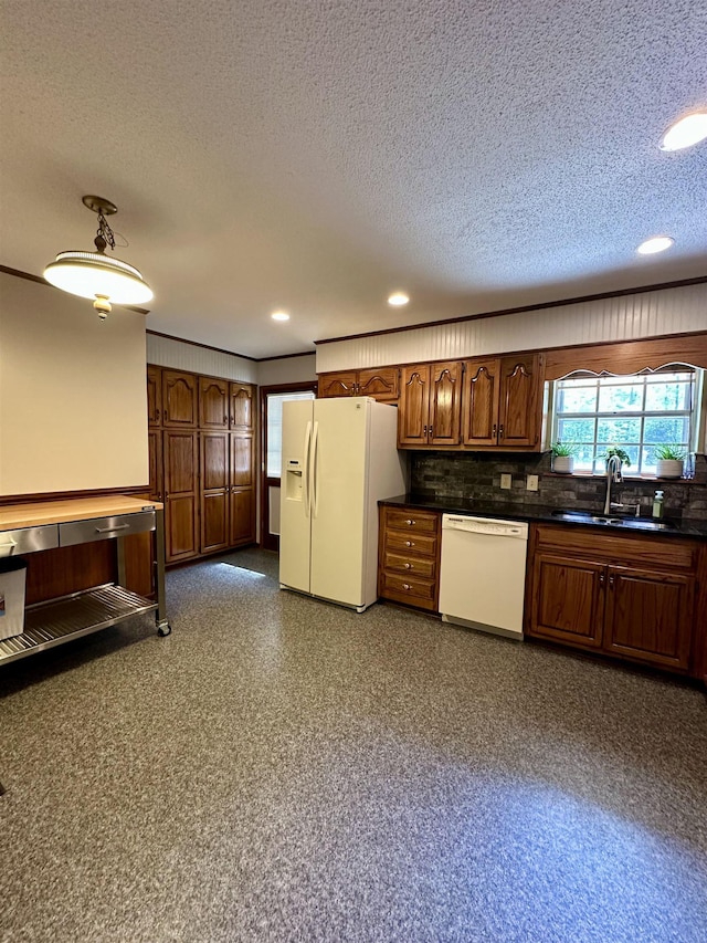 kitchen with decorative backsplash, dark countertops, white appliances, recessed lighting, and a sink