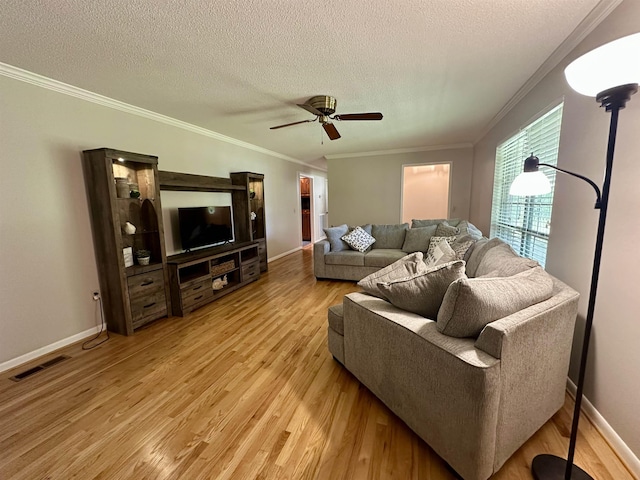 living area with light wood-style floors, ornamental molding, and a textured ceiling