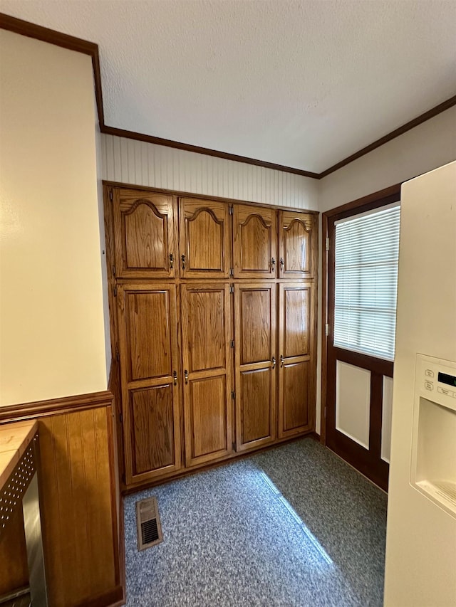 unfurnished bedroom with visible vents, wood walls, wainscoting, crown molding, and a textured ceiling