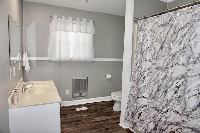 bathroom with heating unit, toilet, wooden walls, vanity, and hardwood / wood-style flooring