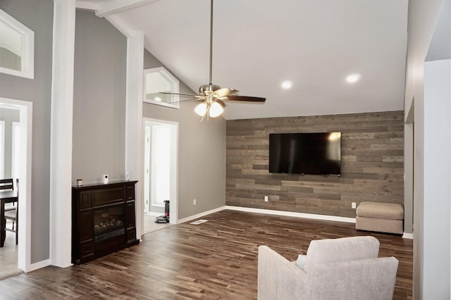 living room featuring ceiling fan, lofted ceiling with beams, dark hardwood / wood-style floors, wood walls, and a fireplace