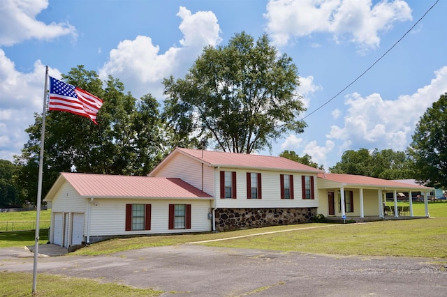 split level home featuring a front lawn, covered porch, and a garage