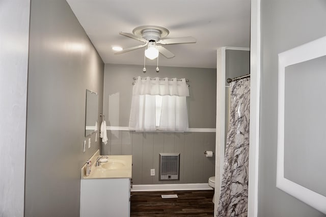 bathroom featuring vanity, heating unit, ceiling fan, hardwood / wood-style floors, and toilet