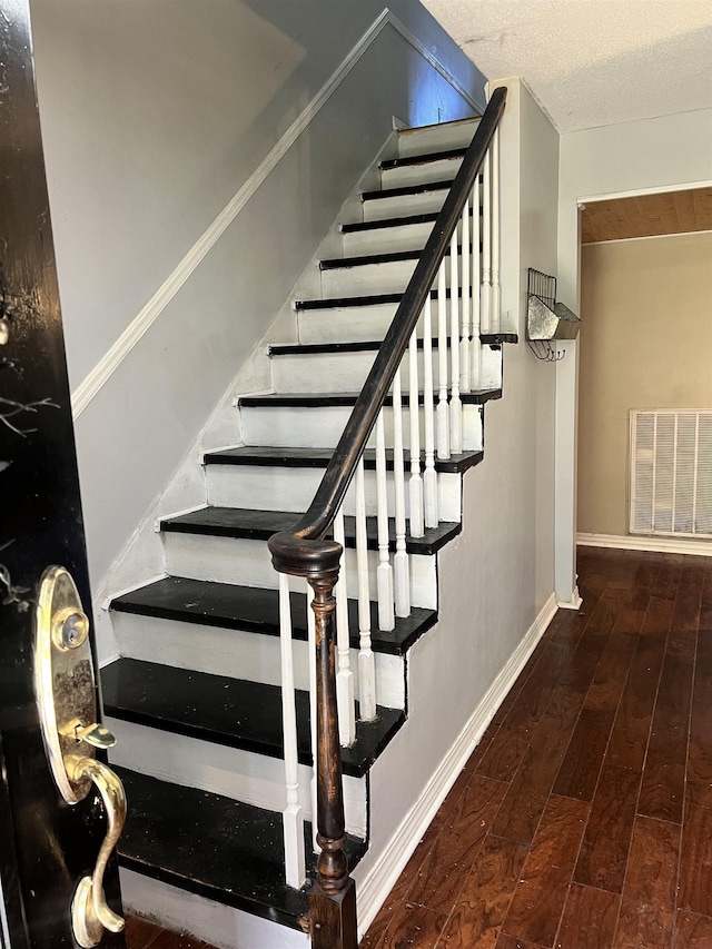 - stairs featuring a textured ceiling and hardwood / wood-style flooring