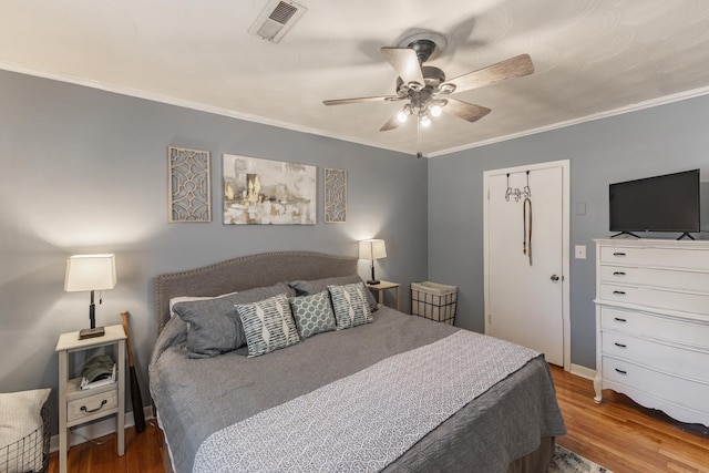 bedroom with ceiling fan, ornamental molding, wood finished floors, and visible vents