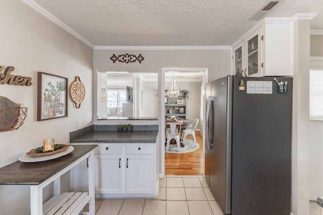 kitchen featuring visible vents, white cabinets, freestanding refrigerator, dark countertops, and glass insert cabinets