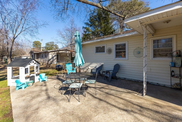 view of patio / terrace with outdoor dining area, an outdoor structure, and a storage unit