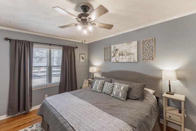 bedroom featuring ornamental molding, ceiling fan, baseboards, and wood finished floors