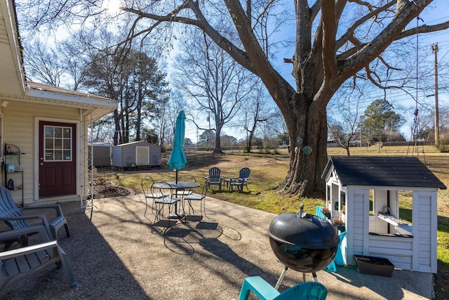 view of yard featuring a patio area, a shed, an outdoor structure, and outdoor dining space