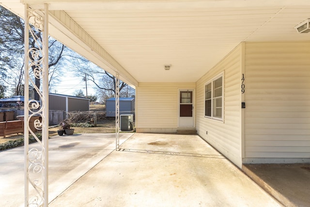 view of patio / terrace with central AC, an attached carport, and driveway