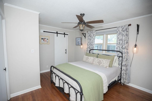  - bedroom featuring a barn door, wood finished floors, a textured ceiling, ornamental molding, and ceiling fan