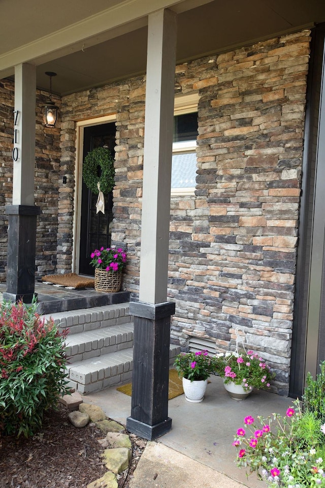  - doorway to property featuring covered porch and stone siding