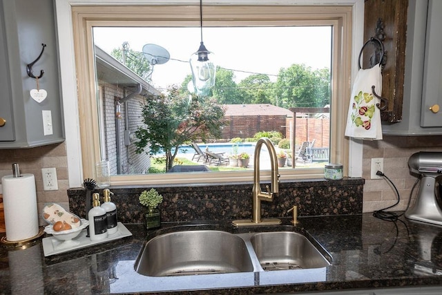  - kitchen view of decorative backsplash, dark stone countertops, and hanging light fixtures