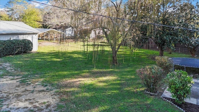 view of yard with a carport and a trampoline