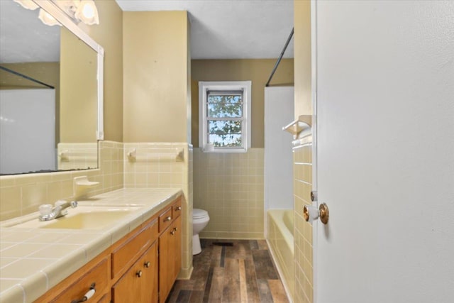 full bathroom featuring vanity, tile walls, washtub / shower combination, hardwood / wood-style floors, and toilet