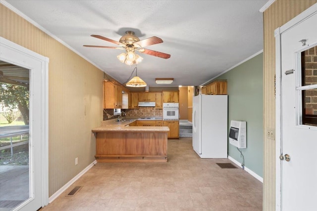 kitchen featuring kitchen peninsula, white appliances, heating unit, and crown molding