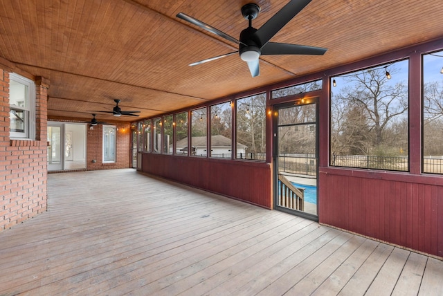 unfurnished sunroom featuring wood ceiling and ceiling fan