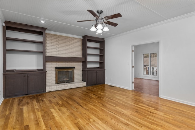 unfurnished living room featuring light hardwood / wood-style flooring, ornamental molding, built in features, ceiling fan, and a fireplace