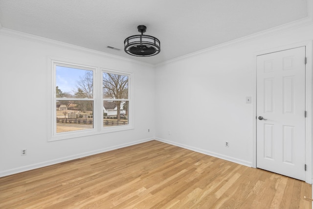 spare room featuring crown molding, a textured ceiling, and light hardwood / wood-style floors