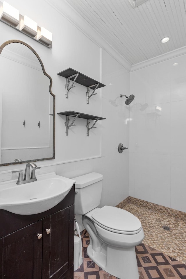 bathroom with crown molding, vanity, toilet, and a tile shower