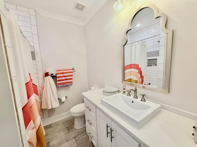 - bathroom with vanity, toilet, a shower with shower curtain, ornamental molding, and baseboards