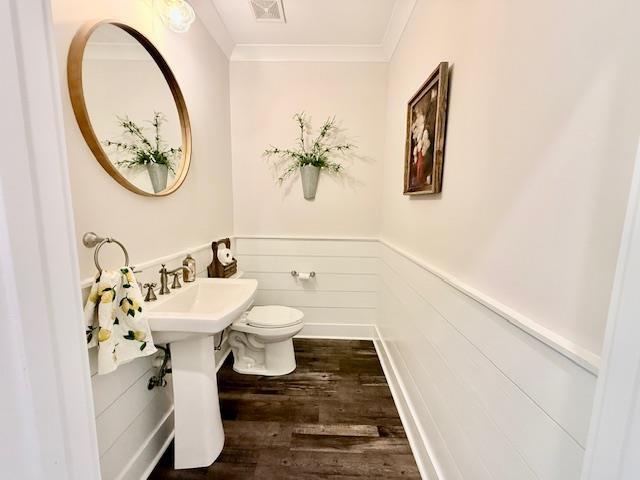  - half bath featuring toilet, crown molding, wainscoting, wood finished floors, and a sink