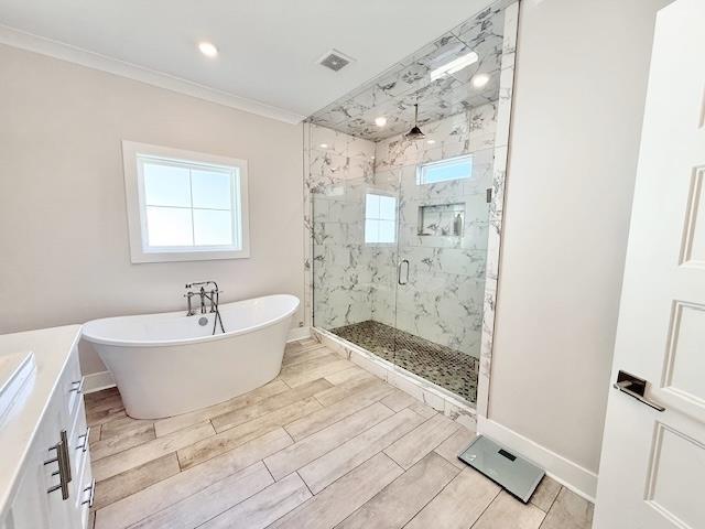 - full bathroom featuring a marble finish shower, baseboards, a soaking tub, ornamental molding, and wood finish floors